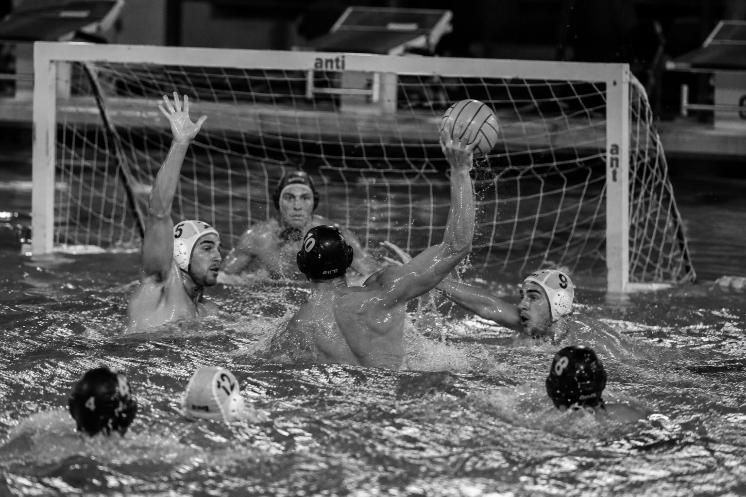 Water polo players contesting the ball in front of the goal